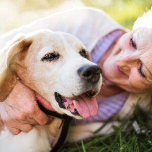 Woman gently holding a happy dog outdoors, showing the loving connection between pets and their people.