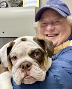 Cat Malkin smiling while holding a bulldog, showing the close bond between pets and their people.